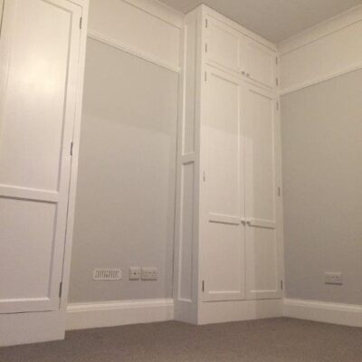 White fitted wardrobe doors in the corner of a bedroom